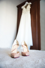 Wedding dress and wedding shoes on the bed.