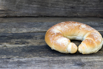 Big sweet appetizing bagel bun close-up on a wooden background and copy space