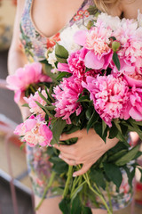 Beautiful girl in a dress with a bouquet of pink peonies in the hands near a vintage carousel