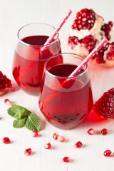 A glass of pomegranate juice with fresh pomegranate fruits on wooden table. Vitamins and minerals. Healthy drink concept.