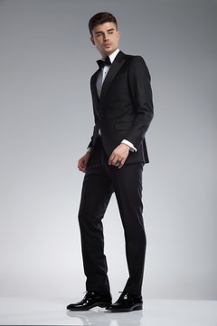 young man in tuxedo standing and looking down to side