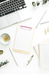 Flat lay office workspace with blank clipboard, laptop and stationery on white background. Top view minimal mock up template blog concept.