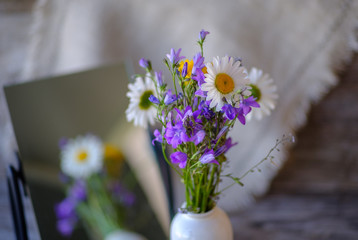 bouquet of wild flowers on a wooden table with a reflection in the mirror
