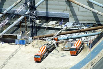 Colored trucks supplying cement and concrete to a construction work site.