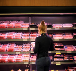 Woman purchasing a packet of meat at the supermarket