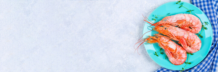 Large royal raw frozen prawns on a blue plate with thyme and basil on a concrete table. Red shrimps. Top view.