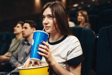 Obraz premium Woman with beverage and popcorn sitting in cinema
