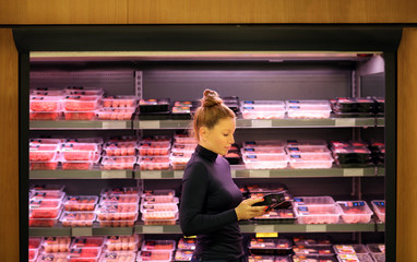Woman purchasing a packet of meat at the supermarket 
