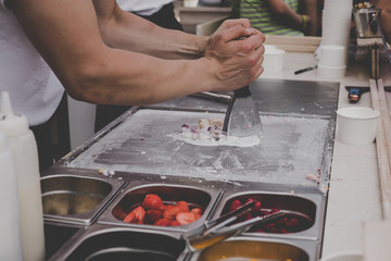 Cooking delicious ice cream rolls at street food market