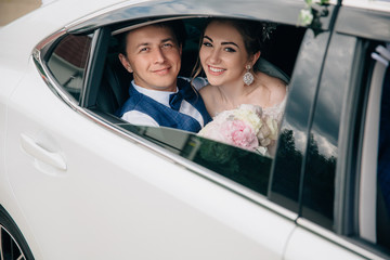 A man and a woman are hugging in the back seat of the car. Portrait of lovers looking at the open window of the car and smiling.