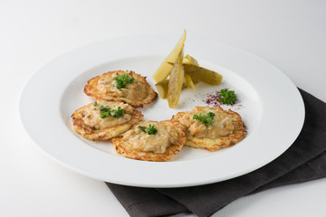 Vegeterian hash brown with pickles and dill on white plate.