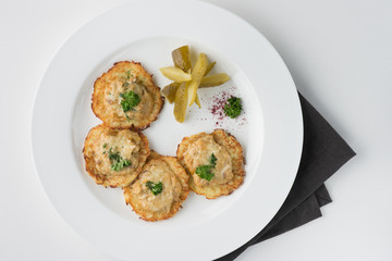 Vegeterian hash brown with pickles and dill on white plate. top view