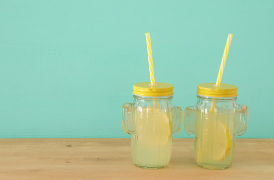 Image of fresh lemonade drink in cute cactus shape glasses over wooden table. Tropical summer romantic vacation concept.