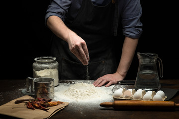 Hand strewing flour to make a dough on wooden table