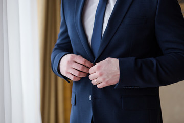 Businessman wears a jacket,male hands closeup,groom getting ready in the morning before wedding ceremony