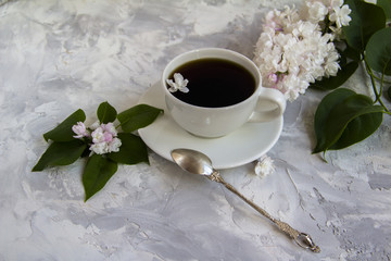 Cup of coffee serving with lilac and leaves