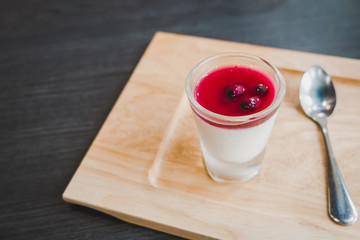 Close up of a tasty panna cotta with red syrup on wooden dish