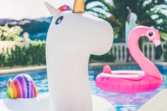 Inflatable colorful white unicorn and pink flamingo at the swim pool. Holidays weekend in the swimming pool with plastic toys. Relaxation and fun concept