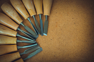 Tools for woodcarving on brown rough background top view