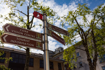 tourist information and direction signs in English and Gaelic Language on a street pole, Cork city...