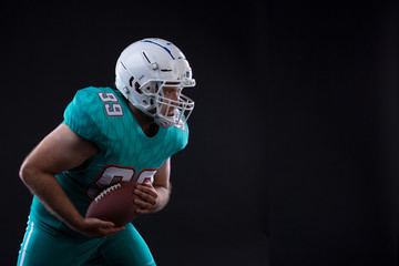 Portrait of American football player holding a ball in both his arms. Copy space. Rugby