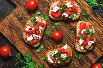 Italian bruschetta with cherry tomatoes and cheese on crispy toast. The view from above, flat lay.