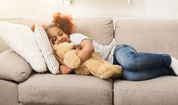 Little happy african-american girl sleeping on couch at home