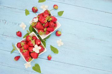 Naklejka na ściany i meble Fresh strawberry in white bowls on blue wooden board