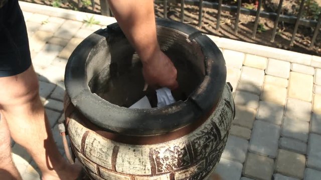 Scorching, heating tandoor. Ignition of paper and loading pieces of wood.
