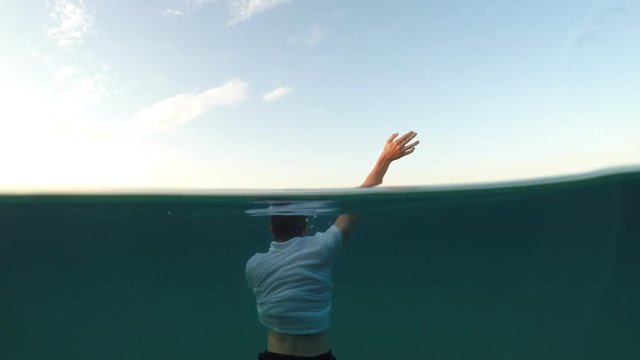 young man sinking into the sea