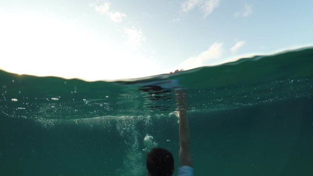 young man sinking into the sea