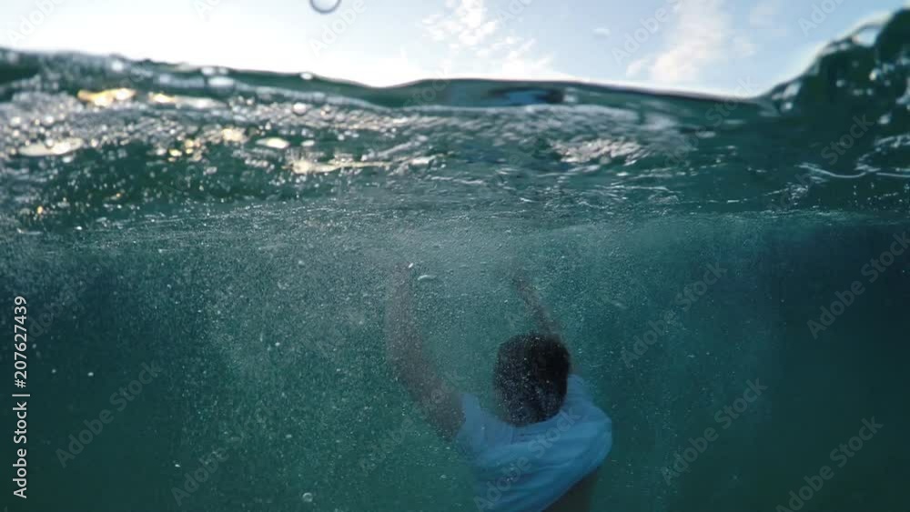 Wall mural young man sinking into the sea