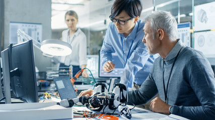 Two Engineers Talking while Working with Robot, Manipulating its Responses and Checking Data with...