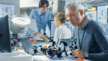 Electronics Engineer Works with Robot, Manipulating its Responses and Checking Data with Laptop Computer. Computer Science Research Laboratory with Specialists Working.