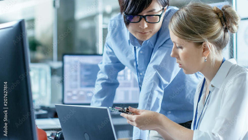 Poster female computer scientists connects circuit board to her laptop and starts programming it. she works
