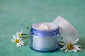   Natural cosmetics for face and body skin care. A round jar with cream and fresh chamomile flowers...