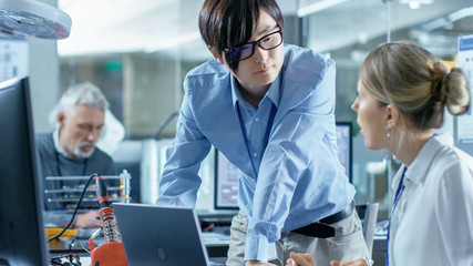 Obraz premium Female Computer Scientists Connects Circuit Board to Her Laptop with Mock-up Green Screen. She Works in the Technologically Advanced Laboratory.
