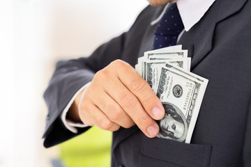 Businessman saving us dollar banknote to shirt pocket.