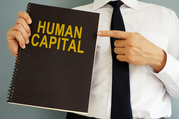 Human Capital concept. Manager holding book.