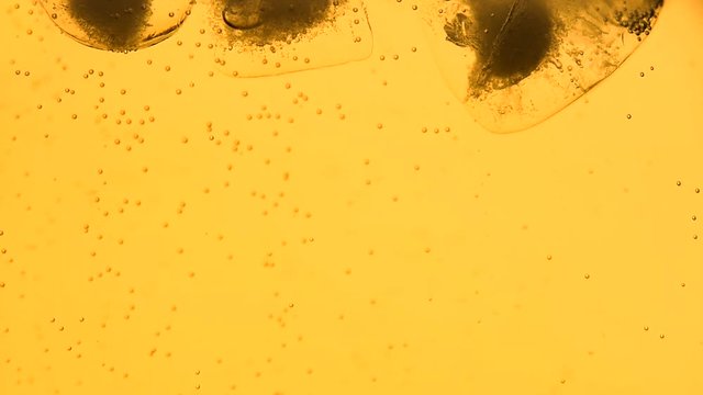 Extreme close up sparkling wine, soda water or lemonade with ice cubes in glass, low angle side view, slow motion