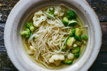 Hot homemade healthy vegan vegetable soup with noodles in plate top view