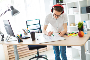 Obraz premium A young man with glasses and headphones draws a marker on the magnetic board.