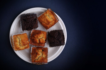 A few flavor of fluffy muffins on top of ceramic plate.