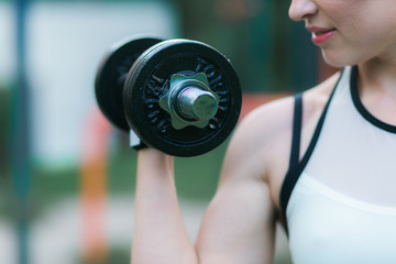 Fototapeta na wymiar Woman workout with dumbbell outdoor, biceps exercise closeup