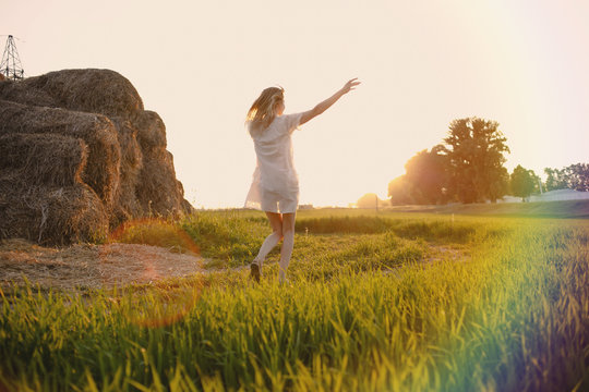 Hello, June! The concept of summer. Girl on the field with green wheat, welcomes the first day of summer