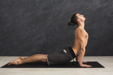 Man practicing yoga at gray background