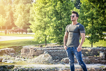 Fototapeta premium Handsome muscular man with tattoo posing in European luxury garden in Turin, Italy
