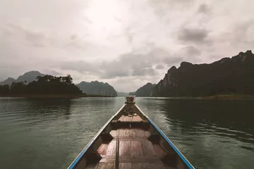 Fototapeten Naturpark The boat sailed forward with a view of mountains and clouds.  © lufeethebear