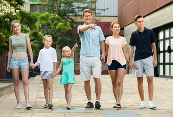 Portrait of large family of six standing pointing with finger together outdoors