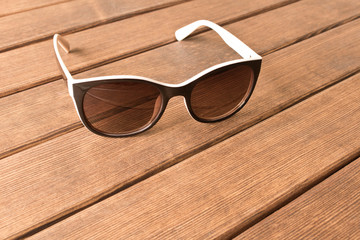 Fototapeta na wymiar Sunglasses on a wooden table. The concept of summer. Empty text space